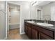 Bathroom featuring double sinks with granite counters and brown cabinets, plus a tub with tiled surround at 14050 Arbor Pines Dr, Riverview, FL 33579