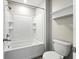 Bright bathroom featuring a white tub with shower, tile surround, shelves, and white toilet at 14050 Arbor Pines Dr, Riverview, FL 33579