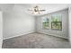 Neutral bedroom featuring two windows with a ceiling fan and plush carpet flooring at 14050 Arbor Pines Dr, Riverview, FL 33579
