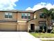 Two-story townhome with a beige exterior, well-maintained landscaping, and an attached two-car garage at 14050 Arbor Pines Dr, Riverview, FL 33579