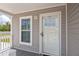 Close-up of the front porch with gray siding, white trim, and a storm door at 1423 Venetia St, Nokomis, FL 34275
