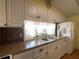 Close-up of a kitchen featuring white cabinets and laminate countertops, and a kitchen window with lace valance at 1710 7Th Sw St # 24, Ruskin, FL 33570