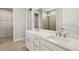 Modern bathroom featuring double sinks with white cabinetry and a glass-enclosed shower at 17800 Solstice Ave, Venice, FL 34293