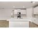 Bright kitchen features white cabinets, a center island with sink, and modern appliances at 17800 Solstice Ave, Venice, FL 34293