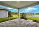 A covered patio with stone flooring overlooking a well maintained yard and lake view at 17800 Solstice Ave, Venice, FL 34293