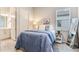 Stylishly staged bedroom with a blue duvet, bright window and modern wood-look tile flooring at 18636 Sailors Delight Pass, Land O Lakes, FL 34638