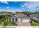 Inviting single-story home featuring a brick driveway, two-car garage, and charming covered porch with stone accents at 18636 Sailors Delight Pass, Land O Lakes, FL 34638