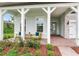 Inviting front porch with brick floor, comfortable seating, white columns, and beautifully landscaped garden at 18636 Sailors Delight Pass, Land O Lakes, FL 34638