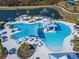 Aerial view of a stunning community pool featuring a sunshade, in-pool seating, and palm trees at 18636 Sailors Delight Pass, Land O Lakes, FL 34638