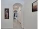 Hallway with tiled floors featuring an arched ceiling, with artwork, leading to the living spaces at 1967 Hovenweep Rd, Wesley Chapel, FL 33543