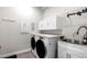 Bright laundry room with modern appliances, cabinet storage, and a stainless steel sink at 20647 Ovid Ln, Venice, FL 34293