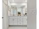 Bright bathroom featuring double sinks with white cabinets, decorative mirrors, and modern fixtures at 22287 Storybook Cabin Way, Land O Lakes, FL 34637