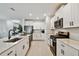 Modern kitchen with stainless steel appliances, white cabinets, and a large island with a sink and faucet at 22287 Storybook Cabin Way, Land O Lakes, FL 34637