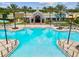 Stunning community pool with palm trees, lounge chairs and colorful clubhouse in a resort style setting at 22287 Storybook Cabin Way, Land O Lakes, FL 34637