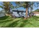 Exterior view of the back of a blue house, featuring a well-maintained lawn and mature trees at 2418 N Links Ave, Sarasota, FL 34234