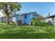 A cozy blue home with a quaint backyard, featuring a small white bench and verdant lawn at 2418 N Links Ave, Sarasota, FL 34234