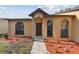Home exterior featuring brick accents around the door and windows, complemented by colorful landscaping at 2974 Sean Way, Palm Harbor, FL 34684