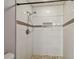 Modern shower with white tiled walls, a mosaic accent stripe, and pebble flooring at 2974 Sean Way, Palm Harbor, FL 34684