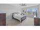 Neutral bedroom featuring a ceiling fan, carpet, and windows overlooking the neighborhood at 33645 Elm Hill Br, Wesley Chapel, FL 33545