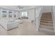 Bright living room with tile flooring, a large sectional sofa, and a staircase to the second floor at 33645 Elm Hill Br, Wesley Chapel, FL 33545