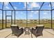 Cozy screened patio with comfortable seating offers a tranquil outdoor space overlooking a picturesque lake at 33645 Elm Hill Br, Wesley Chapel, FL 33545