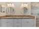 Bathroom featuring a double sink vanity with granite countertops, and decorative round mirrors and a glass shower at 3710 W Tacon St, Tampa, FL 33629