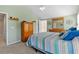 Light bedroom with light green walls, carpet, dresser, bed with striped blanket and doorway at 3710 W Tacon St, Tampa, FL 33629
