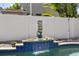Pool featuring a stone fountain, blue tile accents, a privacy fence, and lush landscaping at 3710 W Tacon St, Tampa, FL 33629