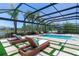 A covered pool area with multiple lounge chairs, manicured green turf, and plenty of seating at 4396 Night Star Trl, Odessa, FL 33556