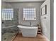Elegant bathroom with a freestanding tub, glass block window, and marble-tiled shower at 4419 Swift Cir, Valrico, FL 33596
