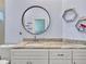 Bathroom features a granite countertop, white cabinets, round mirror, and hexagon decorations at 4419 Swift Cir, Valrico, FL 33596
