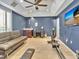 Well-lit exercise room with tile flooring, ceiling fan, brown sofa, desk, weights and a television displaying ocean scenery at 4419 Swift Cir, Valrico, FL 33596