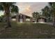 Charming single-story brick home featuring an expansive lawn and a detached two-car garage at sunset at 7169 Spruce Dr, Weeki Wachee, FL 34607