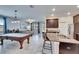 Open kitchen with granite island flowing into living space with pool table and dining area at 7215 Wash Island Dr, Sun City Center, FL 33573