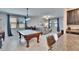Open concept living room with a pool table, a cozy gray sofa, and natural light at 7215 Wash Island Dr, Sun City Center, FL 33573