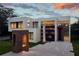 Modern home showcasing unique architecture, with geometric shapes, large windows, and minimalist design under a cloudy sunset sky at 77 Avonwood, Tampa, FL 33625