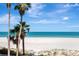 Tropical beach with calm blue ocean and tall palm trees in the distance at 1350 Gulf Blvd # 301, Clearwater Beach, FL 33767