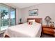 Bright bedroom with sliding glass doors to a balcony, wood floors, and an antique lamp at 1350 Gulf Blvd # 301, Clearwater Beach, FL 33767