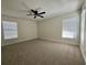 Spacious bedroom featuring neutral carpeting, ceiling fan, and natural light from two windows at 10408 N 50Th St # 1/2, Tampa, FL 33617