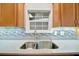 Bright kitchen featuring a double sink, modern backsplash, white countertops, and wooden cabinets at 109 W Saint Lucia Loop, Apollo Beach, FL 33572