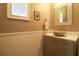 Stylish powder room with wainscoting, unique sink basin, framed mirror and large window at 11105 5Th E St, Treasure Island, FL 33706