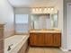 Bathroom featuring double sinks, a large mirror, and a soaking tub with tile surround at 11414 Weston Course Loop, Riverview, FL 33579