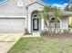 Inviting front entrance with a black framed door, landscaping, and an attached two car garage at 11414 Weston Course Loop, Riverview, FL 33579