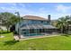 Rear exterior of home featuring a large screened-in patio and pool area, set against a backdrop of lush greenery at 11519 Glenmont Dr, Tampa, FL 33635