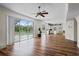 Open living room with wood floors, ceiling fan, and sliding doors with a view of the pool and lake at 11519 Glenmont Dr, Tampa, FL 33635