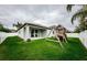 Spacious backyard with lush green grass and a playset, accessible from the covered patio with sliding glass doors at 1155 Lawnview Ter, New Port Richey, FL 34655
