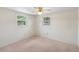 This bedroom offers neutral walls, carpet, two windows, and a ceiling fan with a light at 11705 Ibis Ln, Port Richey, FL 34668