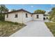 Exterior angle of the home's stucco siding, windows, and concrete driveway under a blue sky at 11705 Ibis Ln, Port Richey, FL 34668