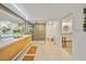 Bright bathroom with glass-enclosed shower, double vanity, and neutral tile floors at 1810 Pine Hill Dr, Safety Harbor, FL 34695