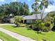 Charming single-story home with a well-manicured lawn, palm trees and a two-car garage at 1810 Pine Hill Dr, Safety Harbor, FL 34695